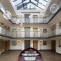 Residential apartment building atrium - Wapping High Street | Main atrium with bespoke industrial chandelier and restored lifeboat | Interior Designers